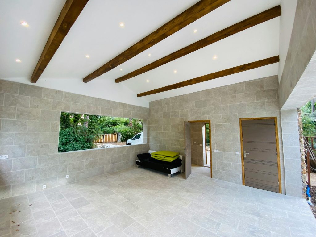 Spacious modern room with natural light, wooden beams, and stone walls.