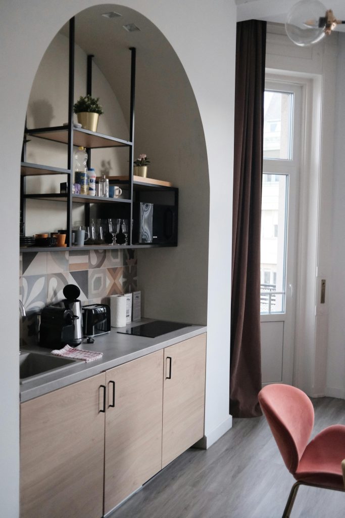 A stylish and contemporary kitchen interior with wooden cabinets and arched shelves in Budapest.