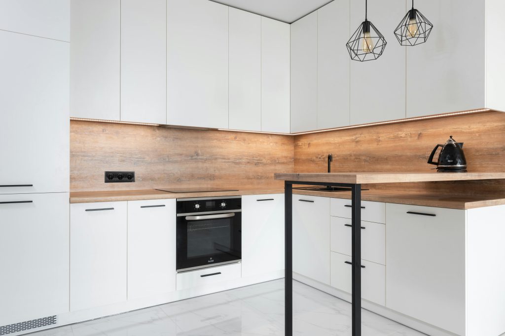 Modern kitchen with contemporary interior with metal geometrical lamps and new white cabinets