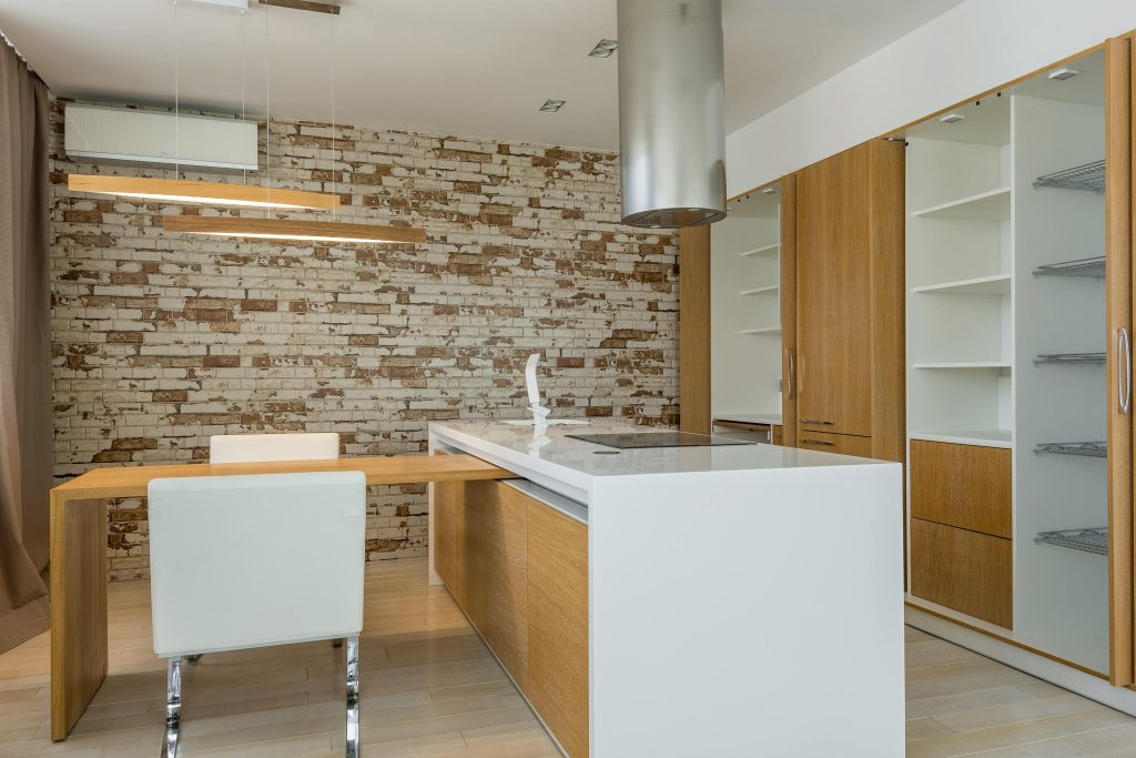 Stylish minimalist kitchen featuring a brick wall and sleek cabinetry.